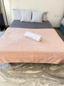 a bed with a pink comforter with a towel on it at Modern studio with pool and fiber connection in Sharjah