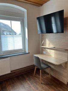 a desk with a television on a wall next to a window at Tilla's Hof in Hamm