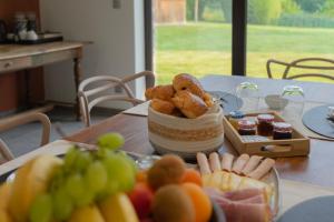a table topped with a basket of food and fruit at Au Petit Canteleu - Bed & Breakfast in Beloeil