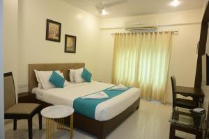 a bedroom with a bed and a chair and a window at Hotel Casa Lorven Near Golf Course in Visakhapatnam