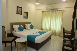 a bedroom with a bed and a chair and a window at Hotel Casa Lorven Near Golf Course in Visakhapatnam +66 photos
