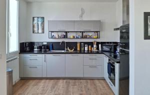 a kitchen with white cabinets and a sink at Charmante Maison Proche Mer in Royan
