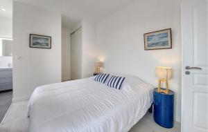 a white bedroom with a bed and two lamps at Charmante Maison Proche Mer in Royan