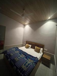 a bedroom with a bed with a blue comforter at Hotel Moonlight in Chhatikara +3 photos