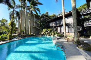 ein Schwimmbad mit Palmen und ein Gebäude in der Unterkunft Stardust Beach Hotel Matabungkay Batangas in Lian