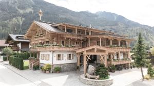 a large wooden house in front of a mountain at BRUGGER ApartHotel in Mayrhofen