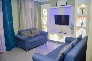 a living room with a blue couch and a tv at Appart Naxel in Kinshasa