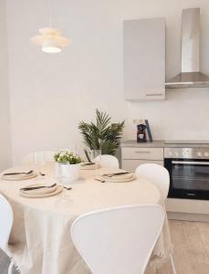 a white kitchen with a table with white chairs at Suites in Brunn am Gebirge in Brunn am Gebirge