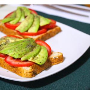 a white plate topped with sandwiches with tomatoes and avocado at Lua Hostal - Arequipa in Arequipa