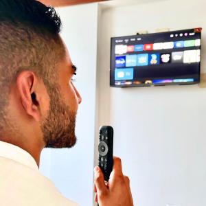 a man holding a remote control in front of a tv at Lua Hostal - Arequipa in Arequipa