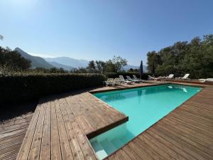 a swimming pool with chairs and a wooden deck at U paradisu in Lumio