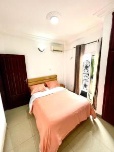 a bedroom with a bed with orange sheets and a window at sidof Redence L&A in Yaoundé
