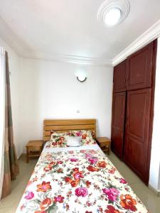 a bedroom with a bed with a floral bedspread at sidof Redence L&A in Yaoundé