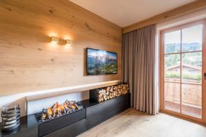 a living room with a fireplace with a tv above it at Minglers Sportalm - Das Gourmet- und Genießerhotel in Kirchberg in Tirol