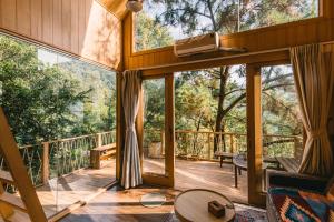 a room with a balcony with a view of trees at U Lesa Retreat - Nhà Bên Rừng in Sóc Sơn