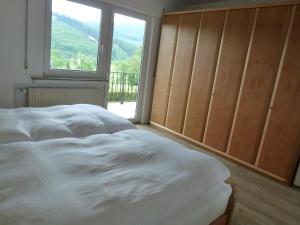 a bedroom with a large white bed and a window at Ferienwohnung Hermann Miß in Bad Berleburg