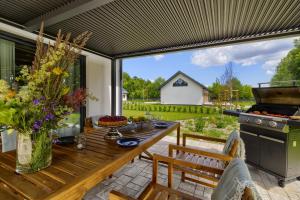 an outdoor patio with a wooden table and a grill at Osada Hipodrom in Łąck