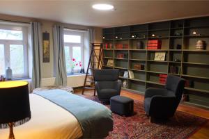 a bedroom with a bed and two chairs and bookshelves at Au Petit Bercail - 2 Chambres d'hôtes pour 2 personnes in Chiny