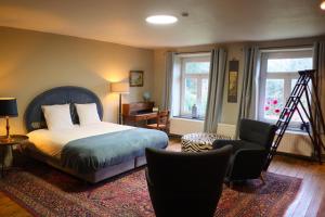 a bedroom with a bed and a chair and windows at Au Petit Bercail - 2 Chambres d'hôtes pour 2 personnes in Chiny