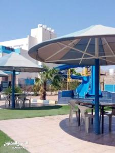 a park with tables and umbrellas and a playground at Larain Plaza Hotel in Aqaba
