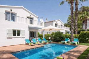 a villa with a swimming pool in front of a house at Villas Serena in Cala Blanca