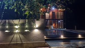 a building at night with a sign that reads guest garden club at Forest Garden Cottages in Deraniyagala