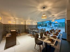 a restaurant with tables and chairs and a large window at Hotel Grand Residency in Mannārakkāt