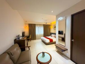 a hotel room with a bed and a couch at Hotel Grand Residency in Mannārakkāt +20 photos