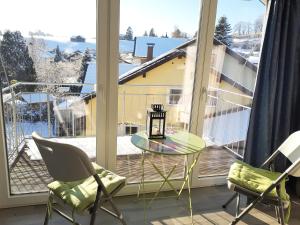 a balcony with a glass table and two chairs and a window at Ferienwohnung Pickenhan in Scheidegg