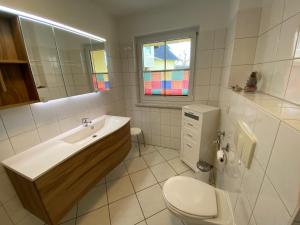 a white bathroom with a sink and a toilet at Gästehaus Siebert in Lobbe +55 photos