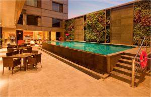a swimming pool in a building with tables and chairs at Radisson Blu Hotel Chennai City Centre in Chennai