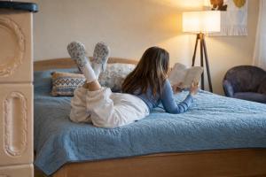 a woman laying on a bed reading a book at Matea Slow Living Home Private Retreat in Čortanovci