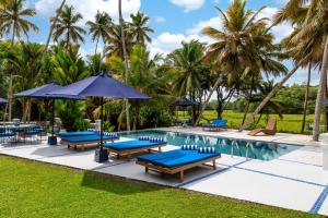 a pool at the resort with blue chairs and umbrellas at Clingendael Weligama in Weligama