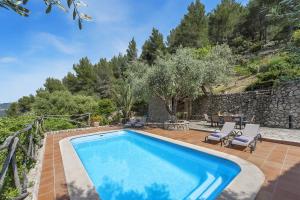 a swimming pool in a yard with a stone wall at Villa Es Barracar Caimari in Caimari