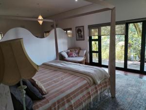 a bedroom with a bed and a couch and windows at Le Chemin Guesthouse - 6 sleeper in Kloof +50 photos