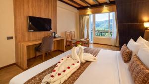 a hotel room with a bed and a desk and a television at Yashshree Dewathang Resort in Lachung