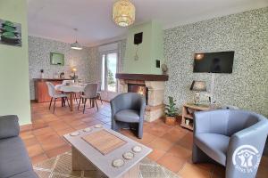 a living room with a fireplace and a table and chairs at Le jardin in Plestin-les-Grèves