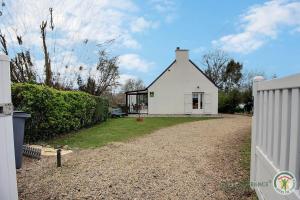 a white house with a fence and a gravel driveway at Le jardin in Plestin-les-Grèves