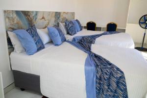 two beds in a room with blue and white pillows at Elclassico Villa in Nyanda