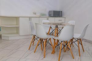 a table and four white chairs in a kitchen at Elclassico Villa in Nyanda +14 photos