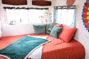 a bed in a room with colorful pillows on it at Caravane cocooning in Saint-Martin-des-Noyers