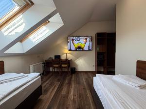 ein Dachzimmer mit zwei Betten und einem Fernseher an der Wand in der Unterkunft Memel Hotel in Klaipėda + 32 Fotos