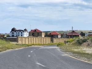 an empty road in front of a fence with houses at Görədil bağ evi in Mekhrably