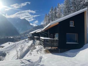 a house in the snow with the mountains in the background at Masura Cabins in Bürserberg