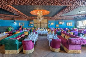 a restaurant with purple and green couches and tables at Kenzi Solazur in Tangier +66 photos