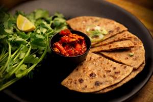 a black plate with a plate of food with a salad and tortillas at Hotel Claytone Near Delhi Airport in New Delhi