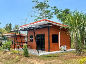 a small wooden house with a porch at Lanta Baan Suan Yoo Dee in Ban Nong Chaeng