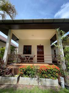a small house with a porch and some flowers at Ron Bungalow in Bang Tao Beach