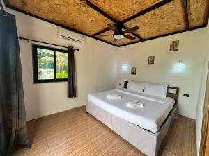 a bedroom with a large white bed with a ceiling at Lanta Baan Suan Yoo Dee in Ban Nong Chaeng