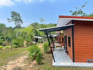 a small house with a porch with a swing at Lanta Baan Suan Yoo Dee in Ban Nong Chaeng